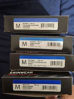 Photo of four stacked boxes with size, style, and color labels visible for each swimwear item.