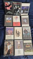 Photo showing twelve vintage cassette tapes in their cases, including albums by Paul McCartney, Alan Jackson, Garth Brooks, and others.
