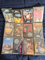 Full view of 12 vintage Time Life rock cassette tapes with colorful illustrated covers, mostly from 1964 to 1969, arranged in three rows on a dark fabric background.