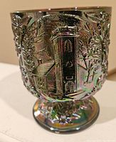 Front panel showing church building surrounded by trees and foliage in relief on iridescent carnival glass surface