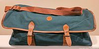 Front view of green canvas travel bag with brown leather buckle straps and Polo logo on round leather patch.