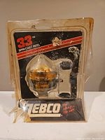 Front view of the vintage Zebco 33 spincast reel in its original plastic blister packaging, showing the reel and handle with Zebco branding.