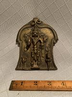 Front view of the bronze plaque with a ruler for scale showing approximately 5.25 by 4 inches.