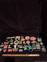 Full view of all 27 fridge magnets arranged on a surface with a ruler for size reference