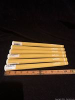 Six yellow golf iron grips stacked with a ruler placed underneath them showing approximately 10 inches in length.