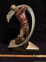 Full front view of the Austin Prod 1999 golfer sculpture showing the entire figure and curved backdrop with ruler for scale.