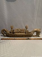 Full side view of the wooden Balinese dragon boat on a white textured cloth background with a measuring ruler for scale.