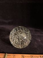 Side angle photo of clear glass spherical paperweight with controlled bubbles inside, showing bubble pattern and condition.