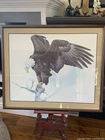 Front view of framed limited edition print depicting bald eagle on branch, showing full artwork and frame with glass reflection.