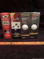 Photo showing four boxes of new golf balls: one Top-Flite XL Distance, one Noodle, and two Callaway RBZ Sport boxes, all new and sealed.