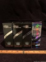 Four unopened boxes of golf balls, three Wilson Staff Luxe and one Wilson Staff Fuzz box.