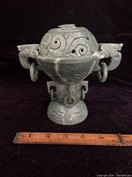 Frontal view of jade lidded incense pot showing the overall shape, carved details, handles with rings, and the missing finial on top.