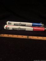 Two golf putter grips in red and blue Tiger Shark branding, still in packaging with a measuring tape showing about 10 inches length.
