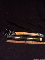 Two putter grips shown next to a ruler measuring approximately 10 inches, one black and yellow unbranded grip and one wrapped Winn putter grip.