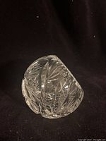 Angled side view of the pinwheel crystal orb ashtray showing detailed cut patterns and unique resting angle.