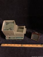 Photo showing both the Pana-vue automatic slide viewer and the Zadiix Jr. 35mm slide viewer side by side with a ruler for scale.
