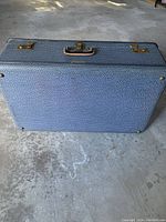 Top view of large vintage blue/grey suitcase showing textured exterior and metal locks with no key.