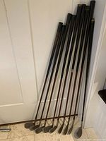 Photo showing 8 Walter Hagen Tom Boy golf irons numbered 1,2,3,4,5,6,8, and another 8. Wooden shafts and metal textured heads visible.