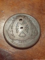 Obverse side of 1837 Lower Canada half penny token showing a wreath enclosing a central design with two holes in the token.