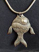 Close-up of the silver tropical fish pendant highlighting detailed pattern work and textured design.