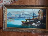 Full view of the framed original acrylic on canvas painting depicting dock scene with boats and buildings in the background.