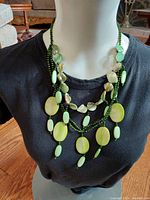 Front view of the emerald beaded necklace trio displayed on a mannequin wearing a black top, showing layering and detail of beads.