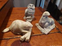 Front view of the three sculptures: beaver, owl, and seal, showing carved details and overall shape on wooden surface.