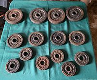 Top down view of assorted vintage Billard barbell weight plates arranged by size on a green cloth.