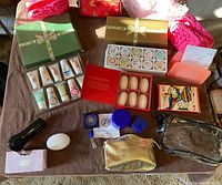 Full lot overview with all items arranged on brown cloth background, showing skin care tubes, soap boxes, cosmetic jars, facial device and makeup bags.