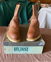 Front view of the brown Hy-Test boots on original box showing toe and pull tab details.