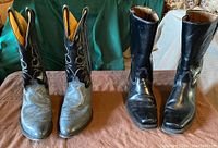 Front and top view of two pairs of men's cowboy boots, black Acme and gray Sheplers, showing shaft and toe details, stitching and wear