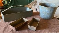 All items displayed together showing toolbox, galvanized bucket and two small metal troughs on a table.
