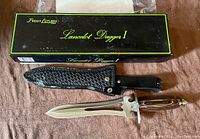 Original box with lettering and leather sheath lying on top, dagger handle and blade also shown