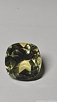 Top-down photo of natural lemon citrine gemstone showing cushion cut facets and clear yellow color.