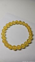 Beaded bracelet with uniform round honey golden amber beads laid flat on a white background.