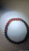 Top view of round bead Baltic amber bracelet showing translucent maple color beads under lighting