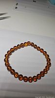 Top view of bracelet showing round amber beads on white background