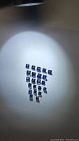 Multiple square-cut royal blue sapphires displayed on a white surface under spotlight.