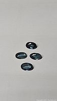 Four oval cut natural blue sapphires laid out on a plain surface, showing color and clarity under natural light.