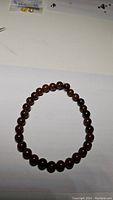 Natural mahogany jasper bead bracelet arranged in a circle on white background.