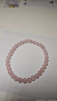 Photo of a natural pink rose quartz bead bracelet laid flat on a white surface