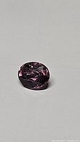 Close-up photo of untreated Myanmar pink spinel gemstone oval cut, 1.04 ct, on a neutral backdrop showing facets and color.