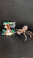 Photo of LEGO Aragog spider with tree and web miniature scene on black background.