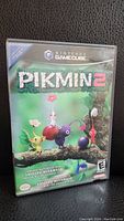 Front cover of Pikmin 2 Nintendo GameCube game case showing colorful Pikmin characters on branch.
