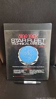 Front black cover of Star Trek Star Fleet Technical Manual with Starfleet Academy emblem and text.