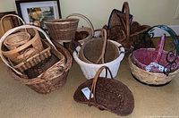 Overview of multiple assorted baskets arranged on carpet, showing different sizes, shapes and styles including woven and painted baskets