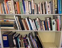 Bookshelves filled with assorted books, including dictionaries, reference materials, and novels. Condition consistent with age and visible wear on spines.