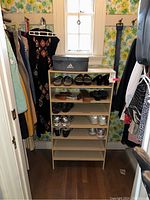 Full closet view showing six-shelf shoe rack with Adidas box on top, multiple pairs of shoes on shelves, assorted hanging garments on either side