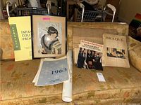 Frontal photo showing the full lot including framed print, folder, posters, magazine, and other ephemera items laid out on a couch