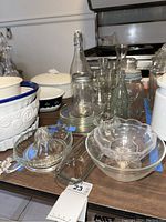 Overview of multiple glassware items including bowls, juice squeezer, jars, and glass plates on a wooden surface